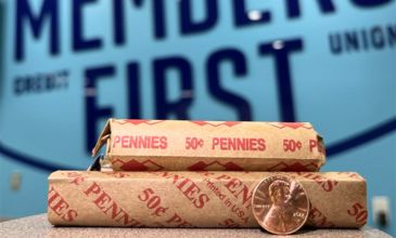 roll of pennies with a lone penny in front of them